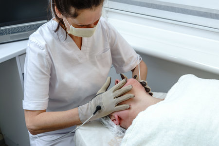 Beautician Performing Electrostimulation Facial Treatment