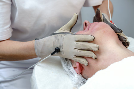 Beautician Performing Electrostimulation Facial Treatment