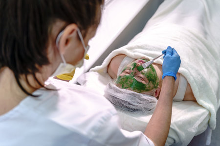 Beautician Applying Herbal Green Face Mask Treatmentの写真素材