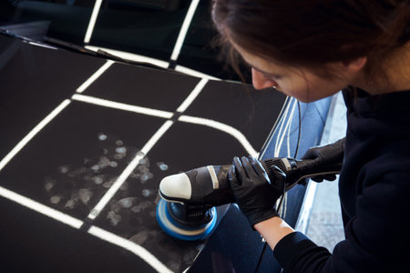 Girl professional car service worker with orbital polishing machineの写真素材