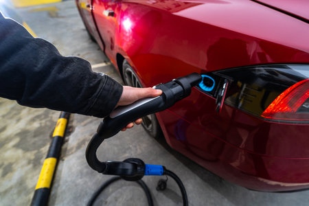 Hand Plugging Electric Car at Charging Stationの写真素材