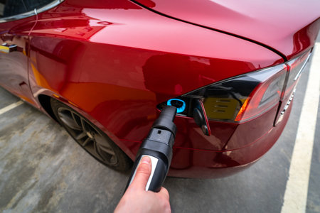 Hand Plugging Electric Car at Charging Stationの写真素材