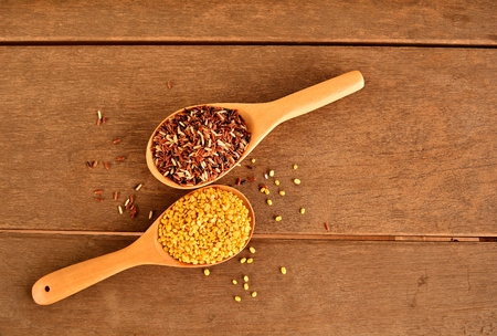 Jasmine red rice and green peas cracked in a wooden spoon on an old wooden floor.の写真素材