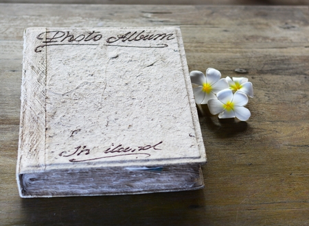 An old photo album on a vintage wooden desk.の写真素材
