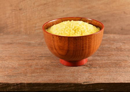Rice cooked with turmeric in a wooden bowl on an old wooden floor.の写真素材