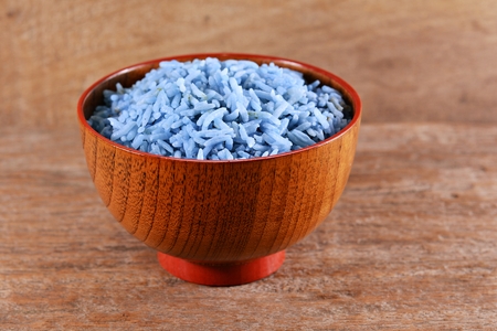 Rice cooked with water pea flower in a wooden bowl on an old wooden floor.の写真素材
