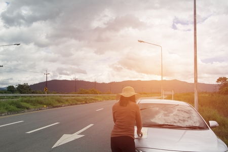 The girl drove the road and lost her way, so the map came out to see the actual area. There is a mountainous backdrop and an orange flare.の写真素材