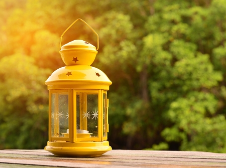 The yellow lamp is placed on a wooden table, the backdrop is blurred and the flares are orange.の写真素材