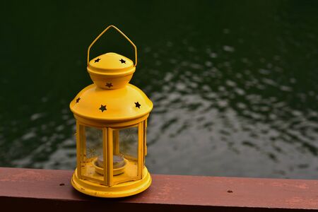 A yellow lamp on the balcony. There is a water floor below and a backdrop.の写真素材
