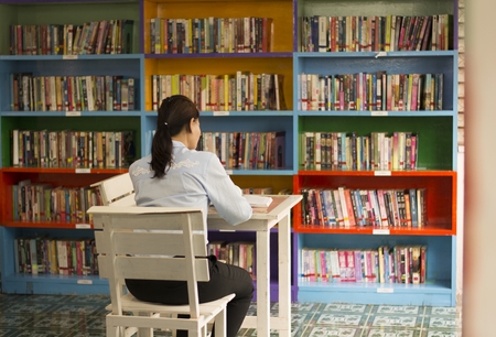 Ladies are reading books in the library. Bookshelf backdrop