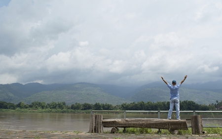 The man stands on a wooden stick, lifting his hands above his head, inhaling the air, full of lungs and excited with the scenery in front.の写真素材