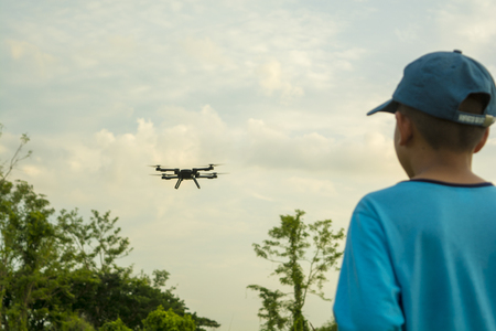 The boys play the dron, the white sky is in the background.の写真素材