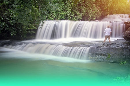 Men wear shorts. Wearing white shirt Wearing a brown hat Looking at the beauty of the waterfall.(Photo shoot Long exposure)の写真素材