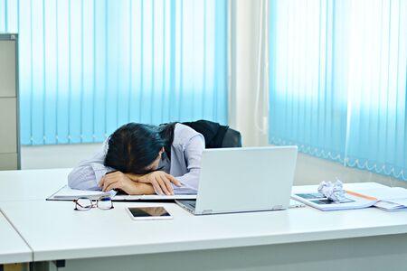 Office workers sleep at work. Due to tired work / Take blue tonesの写真素材