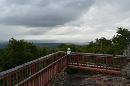A lady in a white shirt and white hat stands on the promenade, looking at the sky clouds in front of you.の写真素材