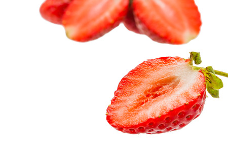 one half of strawberry and blur group of strawberry isolated on whiteの写真素材