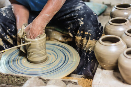 dirty hands making pottery in clay on wheelの写真素材