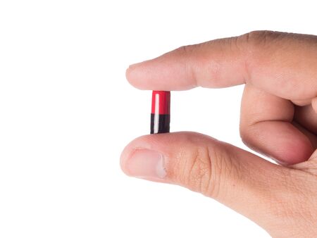 Hand holding a capsule or pill isolated on whiteの写真素材