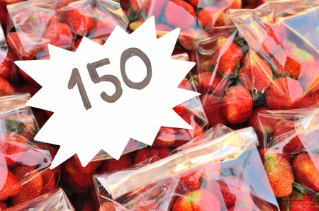 Strawberries in package at market with price tag 
