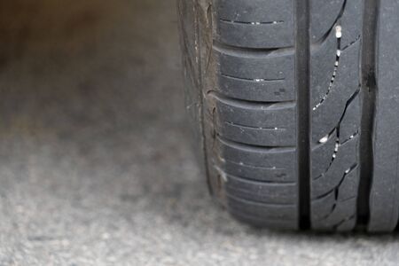 Close up beside tire of car on asphalt road. Rubber patterns with stones have been used on the road.の写真素材