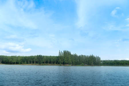 Landscape view of nature Reservoir with light waves. Along the wooden bridge is far away in the tourist attraction. with green trees for backgound under blue sky.の写真素材