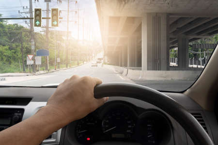 Hand of driving man with console of car inside interior view.  Looking ahead on a junction with a...