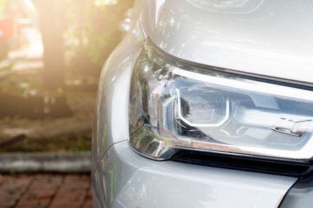 Front headlight of the car parked in the park. Blurred of trees in park area.の写真素材