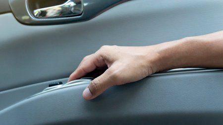 <p>Passenger's hand holds armrests beside the door of car from the inside. Driver finger pulls the windowpane button.</p>の写真素材
