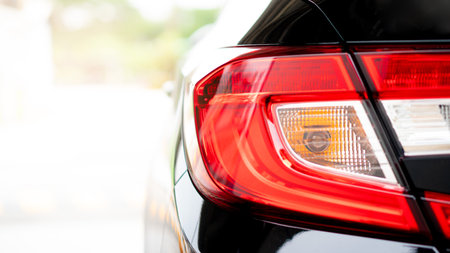 Close up tail light of black car. In the pakring lot. with abstract and blurred of background with...
