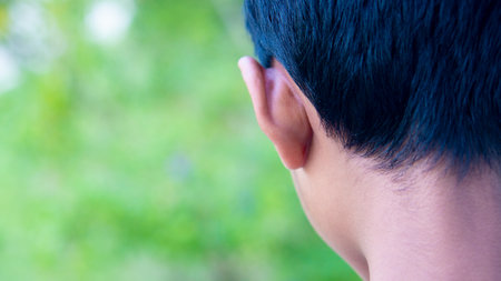 Clouds up corner of the hair. Head of a boy standing with his back. With blurred green nature background.の写真素材