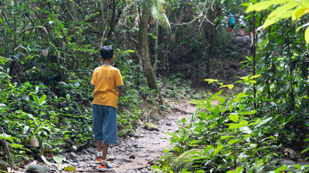 Boy walks in a forest lane in the Khao Chamao Waterfall tourism area. Walking soil road in forest. Travel in Ratyong Thailand.の写真素材