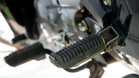 Close up of motorcycle footrest pedals. under view of motercycle stop with stand. Bright of sunlight for background.の写真素材
