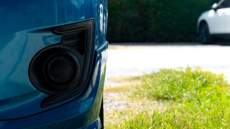 Under front of blue car can see cover of fog lights. Background of soil road and green grass with blurred of front other cars.の写真素材