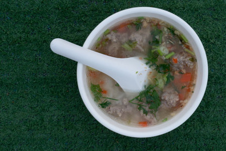 Pork porridge in a bowl ready to serve. There is a spoon placed in the cup. Rice porridge consists...