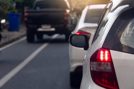 Rear side view of white car on the aspahlt road. Transtport of car turn on brake light in the business time environment of moring time. Traffic congestion and queues of cars.の写真素材