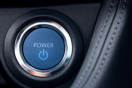 Blue power start engine button with a silver ring surrounding it. The button is illuminated and has...