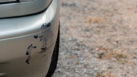 Car bumper with visible scratches and paint damage. Gold colored bumper has dark scuff marks. suggesting a collision or scrape. Background is a blurred textured surface possibly aの写真素材