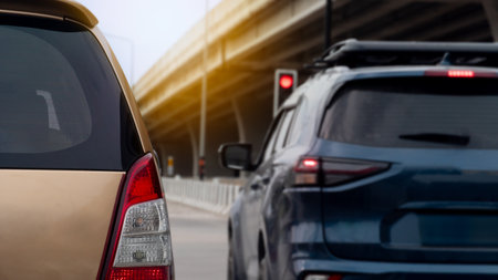 Cars in traffic with a red traffic light visible. Background is blurred suggesting movement or distance with an elevated structure hinting at an overpass or bridge.の写真素材