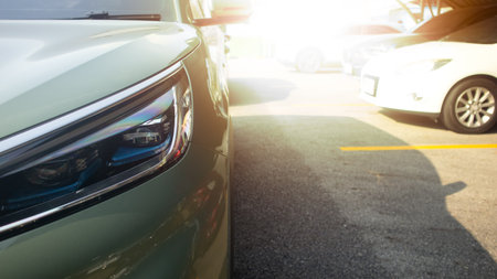 Close up of car soft green color headlight on parking lot. with blurred of other cars in parking lot under roof for background. And strong sunlightの写真素材
