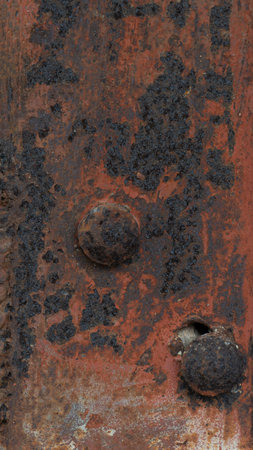 Textured surface with rust and discoloration. Surface appears to be metal with rivets or bumps and...