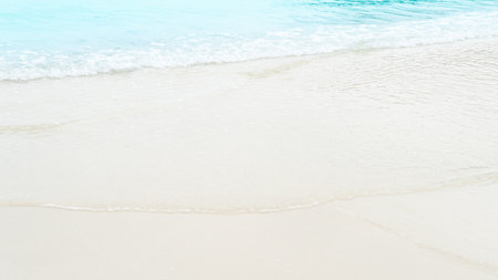 Gentle waves of the sea hitting the soft colored beach. Travel on the sea beach on day time.
