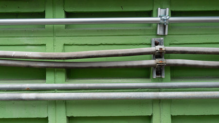 Conduit pipe and flexible pipe attached to pipe clamps. Ventilated walls of green buildings.