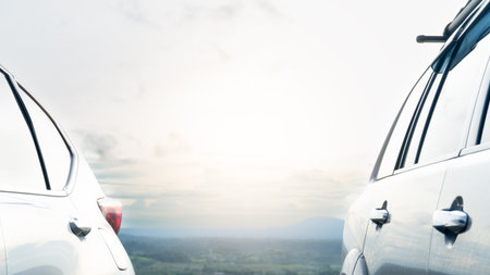 Side view of the rear of both cars. The back is a warm natural landscape. The fields and forests are blurred. With a slight mist and sunlight shining through.の写真素材
