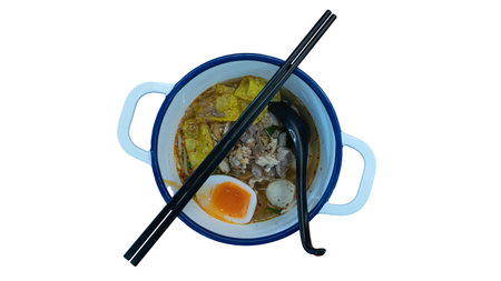 Overhead shot of a delicious bowl of Thai Tom Yum noodles with meat pork and a boiled egg served in...