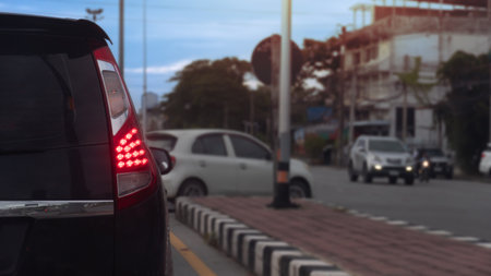 Rear side of car taillight on road in city. Blurred background of car U-turn on the road. Center with are bricks and the base of a streetlight pole. and city in the evening.の写真素材