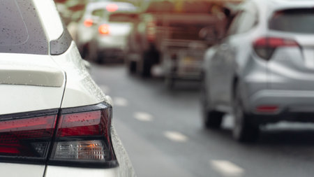 Rear side of white car driving on the road. On body of car with drop of water rain.  à¸ºBlurred...