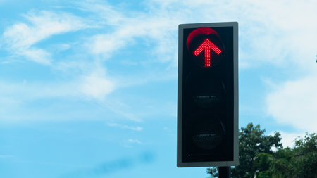Traffic lights with bright red lights. Background of tree under blue sky and white clouds in the...