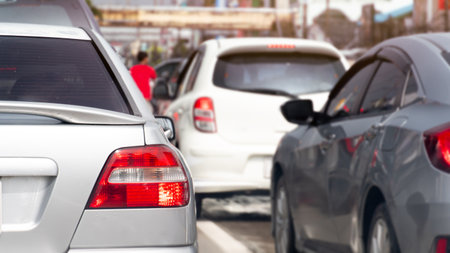 Rear side view of silver car with turn on brake light. Trffic jam on the aspahlt road in the day time. Many cars in the city in business time.の写真素材