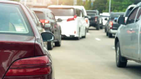 Rear side of red color parked in a line in a curve on the concrete road. With traffic congestion. Blurred of trees for background.の写真素材