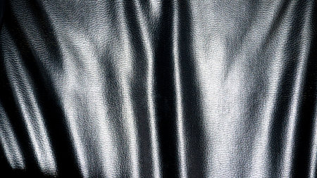 Black wrinkled leather sheet. There is brightness from the incident light. For background and textured.の写真素材